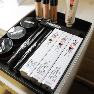 Makeup products including mascara and eyeliner on a tray.